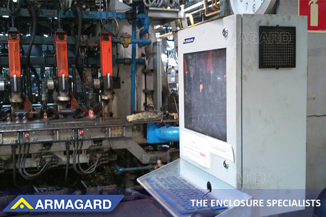 Ett fabriksgolv PC-skåp skyddar en dator och en skrivare i en industriell miljö Ett industriellt fabriksgolv PC-skåp som skyddar en dator i en fabrik